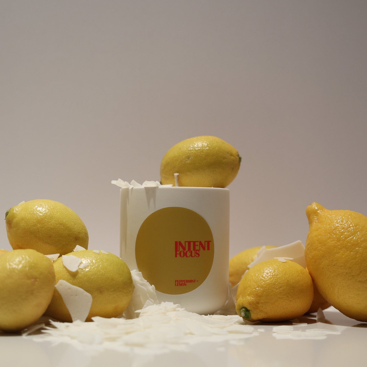 Lemons and a candle labeled 'peppermint and lemon' on a white surface with a light gray background